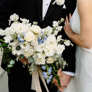 Wedding couple sharing a kiss with floral bouquets in an outdoor setting.