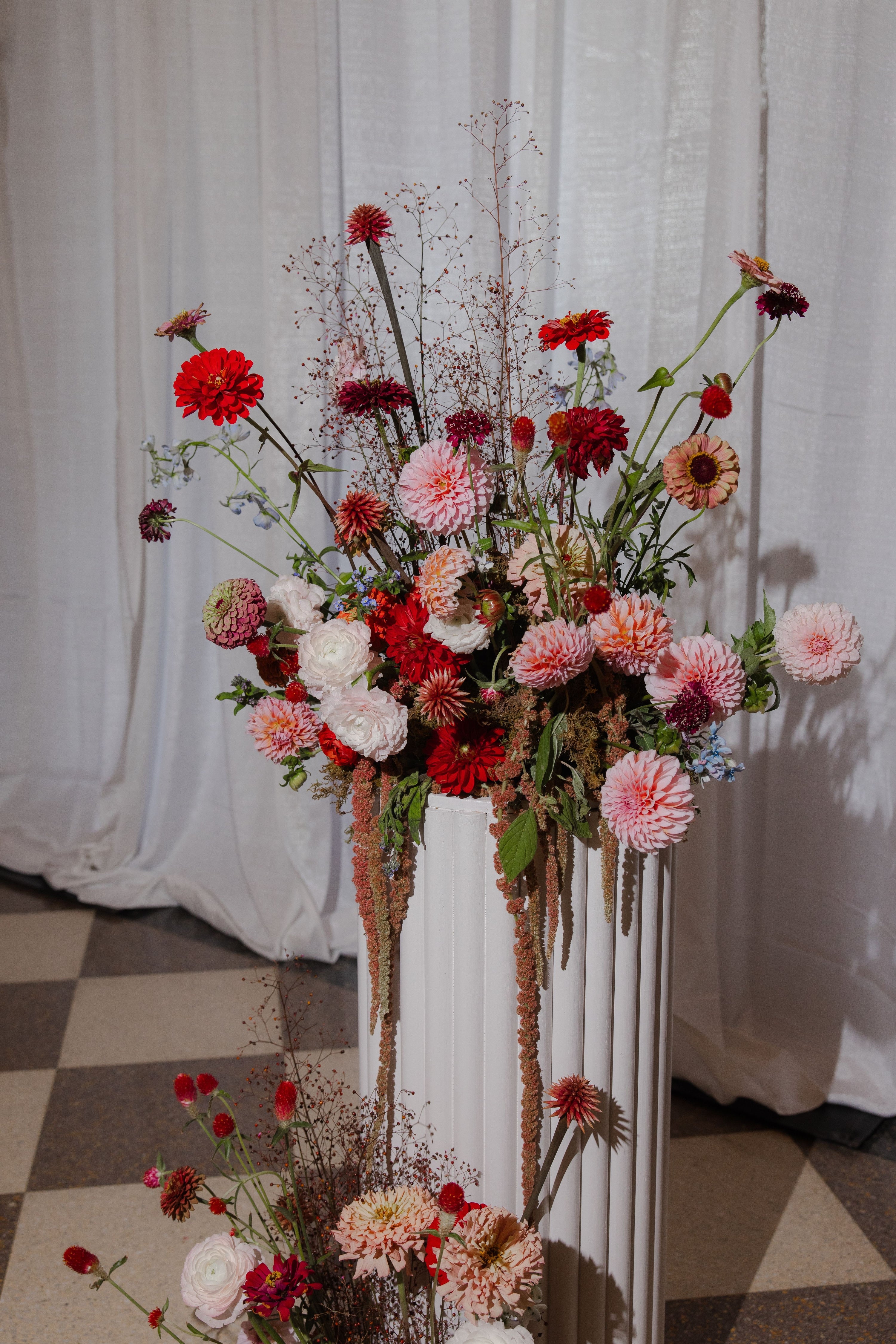 Floral arrangement in a white vase against a white curtain backdrop