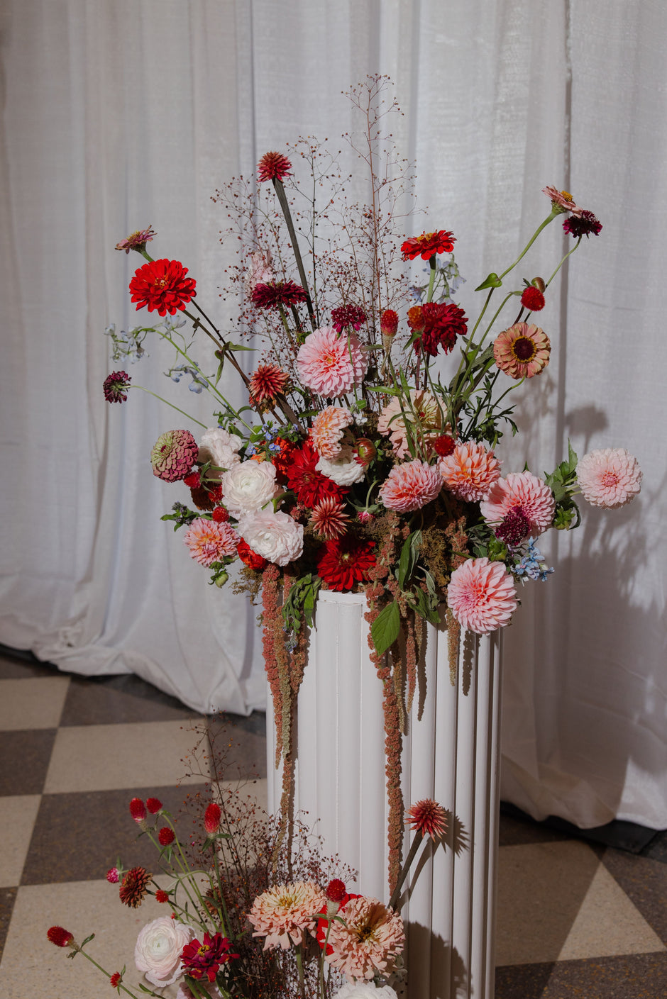 Floral arrangement in a white vase against a white curtain backdrop