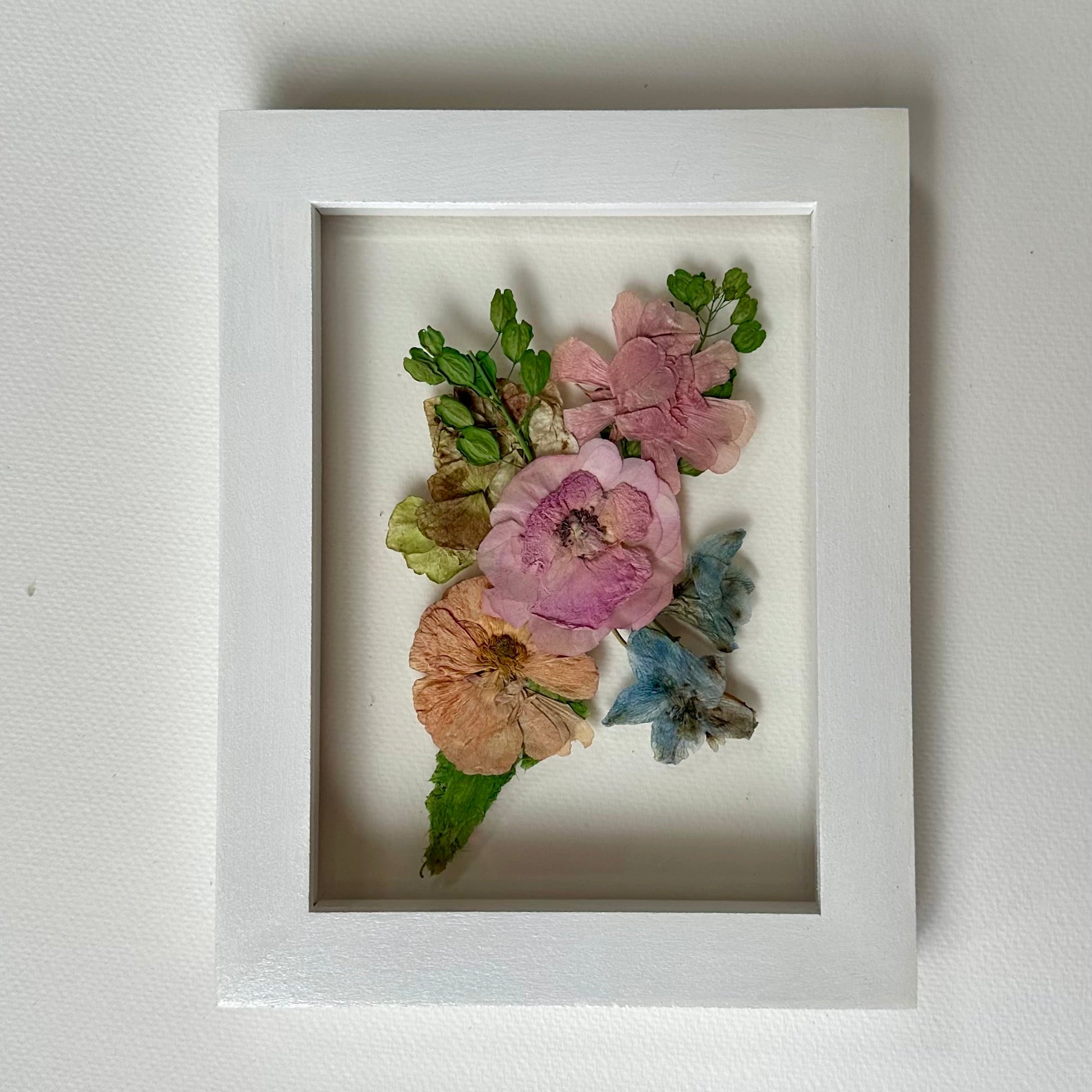 Framed pressed flowers on a light gray background