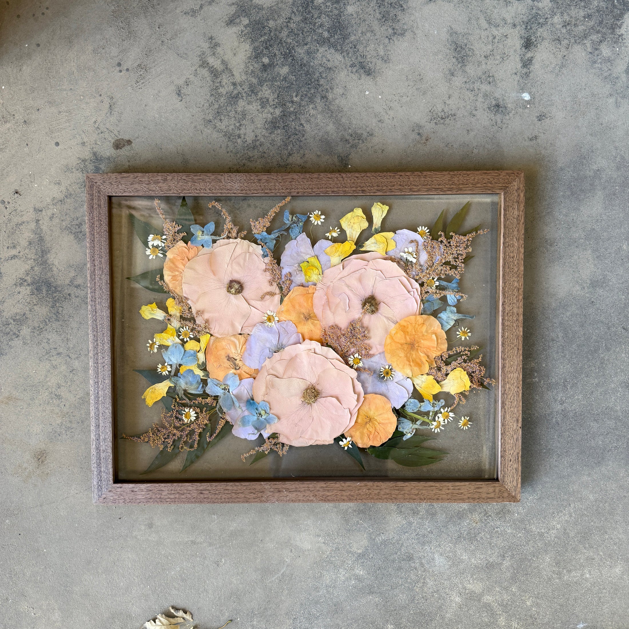Framed floral artwork on a textured concrete floor