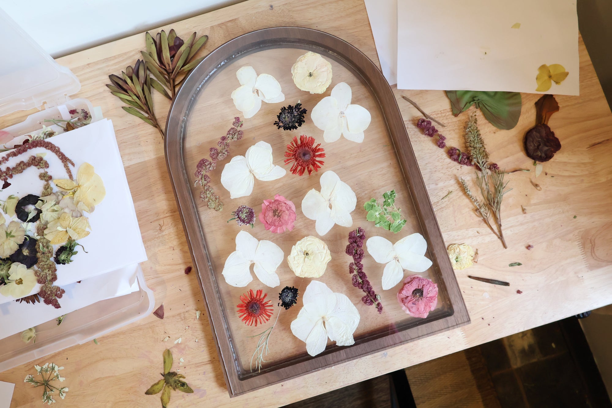Arch-shaped frame with pressed flowers on a wooden surface