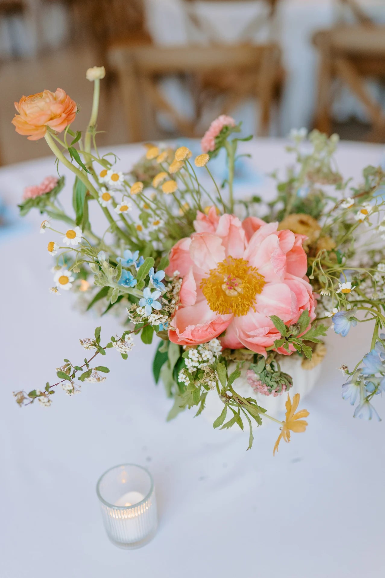 Pink floral arrangement on a table with a candle in the foreground