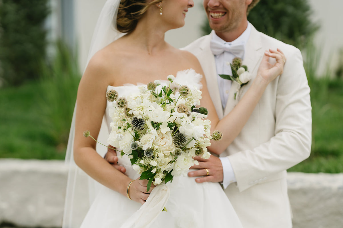 White bridal bouquet of flowers with bride and groom