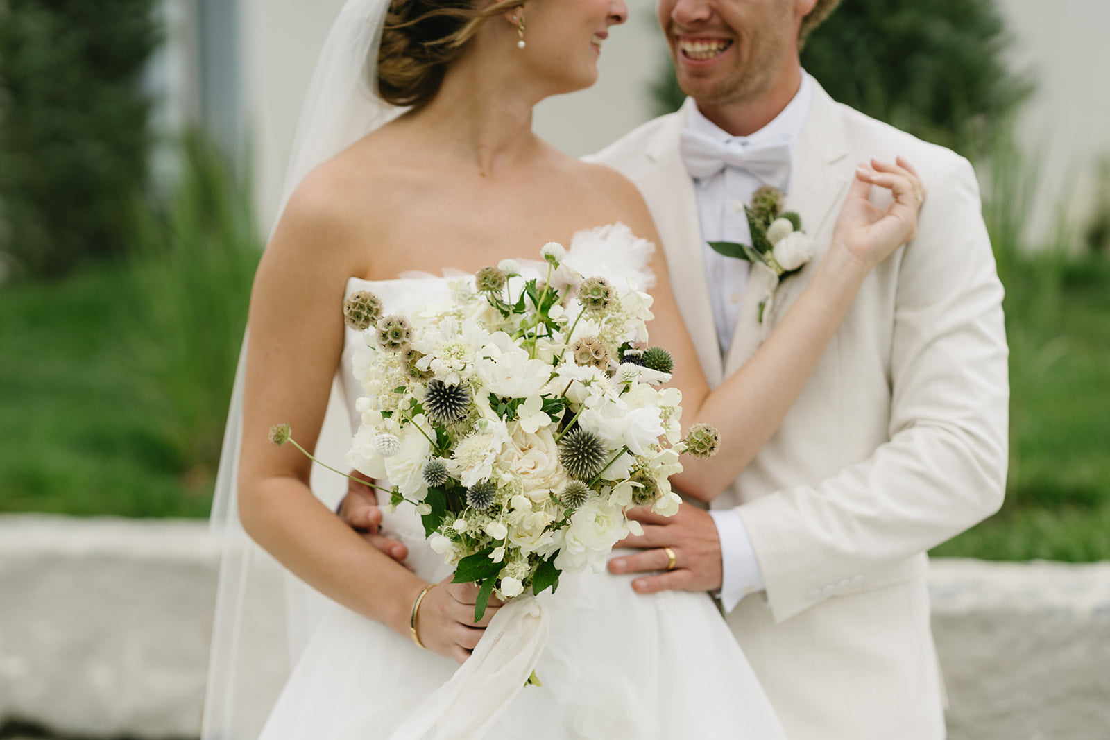 White bridal bouquet of flowers with bride and groom